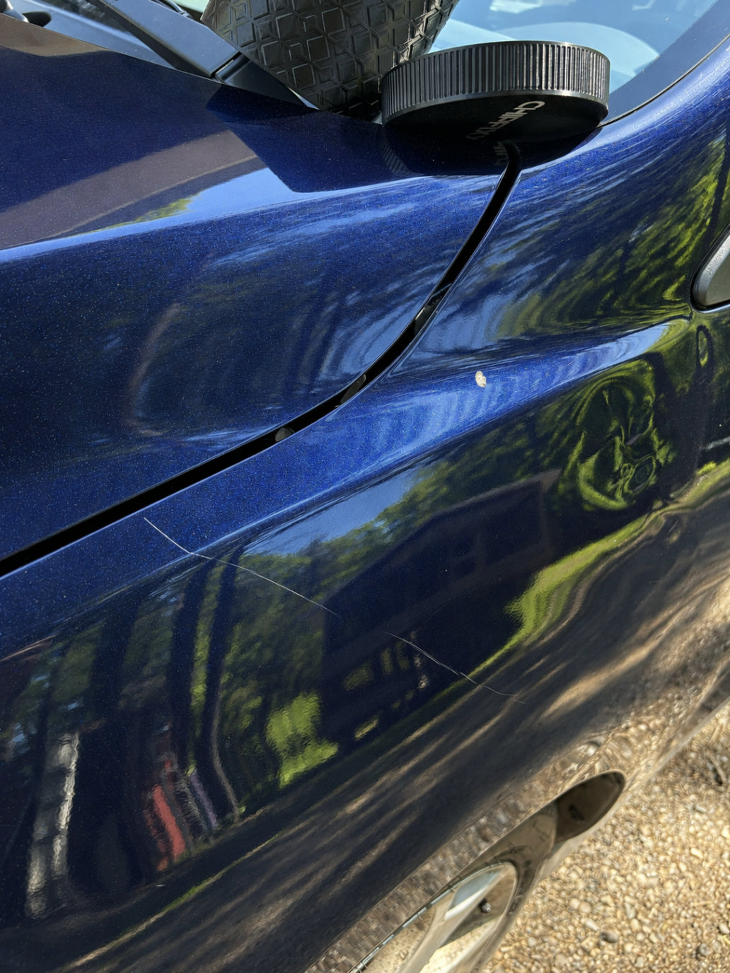 Close-up of a stone chip exposing bare metal on a car panel